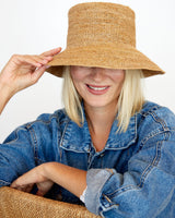 Person wearing a straw hat and denim jacket on a white background