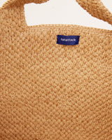 Close-up of a woven bag with a brand label on a white background