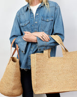 Woman holding two woven bags against a plain background