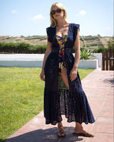 Woman wearing a dark blue eyelet coverup with floral patterns outdoors on a sunny day.