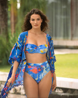 Woman wearing a blue bikini with floral patterns and a matching cover-up in an outdoor setting.