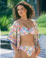 Woman wearing a colorful floral bikini and cover-up standing outdoors.