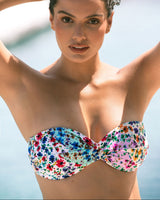 Woman wearing a colorful floral bandeau top against a blurred natural background