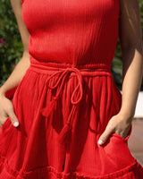 Red dress with a tie waist worn by a person, blurred background