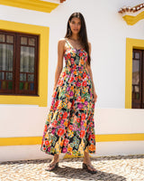 Woman in a colorful floral dress standing in front of a white wall with yellow accents.
