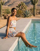 Woman sitting by a pool with cacti and mountains in the background