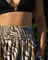Person wearing a black top and zebra-patterned pants with a blurred background
