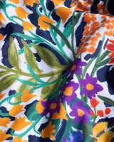 Close-up of a colorful floral fabric with orange, purple, green, and blue patterns.