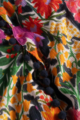 Close-up of a colorful fabric with floral embroidery and tassels.
