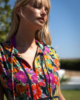 Woman wearing a colorful floral dress against a blue sky.