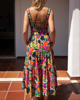 Woman wearing a colorful floral dress standing on a tiled floor.