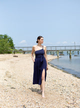 Model standing and looking at water in long navy skirt