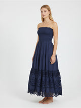 Woman wearing a strapless navy blue dress with lace details on a white background