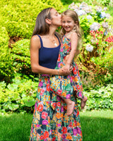 Woman or Mom in a colorful floral dress kissing a young girl in a garden setting