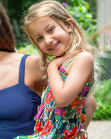 Young girl in a colorful dress sitting outdoors with a blurred background