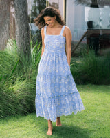 Woman in a blue floral dress standing outdoors on grass