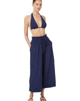 Model wearing navy blue organic cotton beach pants with elastic waistband with drawstring and tassel detail with matching navy blue triangle bikini top