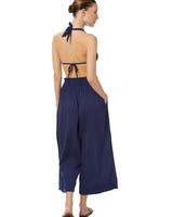 The back of a model wearing navy blue organic cotton beach pants with elastic waistband with drawstring and tassel detail with matching navy lye triangle bikini top