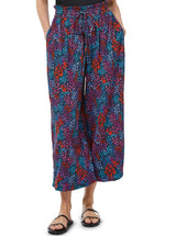 Close up shot of a model wearing a floral pattern organic cotton beach pants  with elastic waistband with drawstring and tassel detail