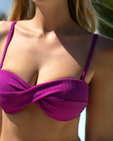 Close-up of a person wearing a purple bikini top with a blurred background