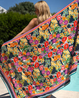 Woman holding a colorful floral towel by a poolside