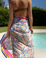 Woman in a colorful floral skirt standing by a pool with greenery in the background