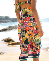 Model wearing a colorful floral dress on a beach