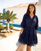 Woman wearing a navy blue dress with lace details in a tropical setting.