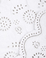 Close-up of a white eyelet fabric with floral cutwork and a wavy scalloped border.