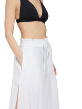 Close up shot of model wearing fresh white midi length skirt with side slits and elastic waistband with drawstring detail with black v-neck bikini top and black sandals
