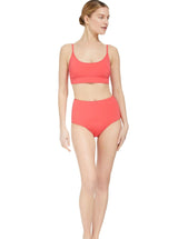 Model wearing a coral scoop neckline bikini top with under-bust band and adjustable straps with matching high rise bikini bottom