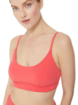 Close up of a model wearing a coral scoop neckline bikini top with under-bust band and adjustable straps with matching high rise bikini bottom