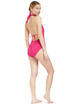 back of Model wearing fuchsia deep plunged one piece swimsuit with an adjustable halter-neck tie and under-bust string