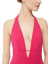 close up shot of Model wearing fuchsia deep plunged one piece swimsuit with an adjustable halter-neck tie and under-bust string
