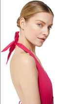 profile view of model wearing fuchsia deep plunged one piece swimsuit with an adjustable halter-neck tie and under-bust string