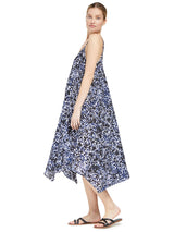 the side of a model posing wearing a black and white leopard print strappy and long flowy dress with adjustable back shoulder straps, and v-neckline front and back with pockets and black sandals