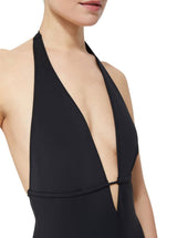 close up shot of Model wearing black deep plunged one piece swimsuit with an adjustable halter-neck tie and under-bust string