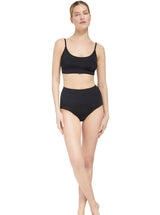 Model getting out of lake and laughing wearing a black scoop neckline bikini top with under-bust band and adjustable straps with matching bottoms