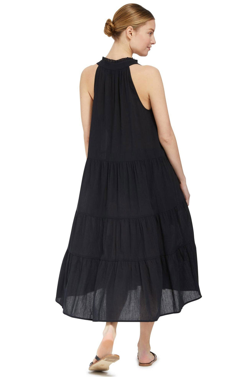 The back of a model wearing a black sleeveless, high neck with ruffle detail, buttoned shirt dress. 