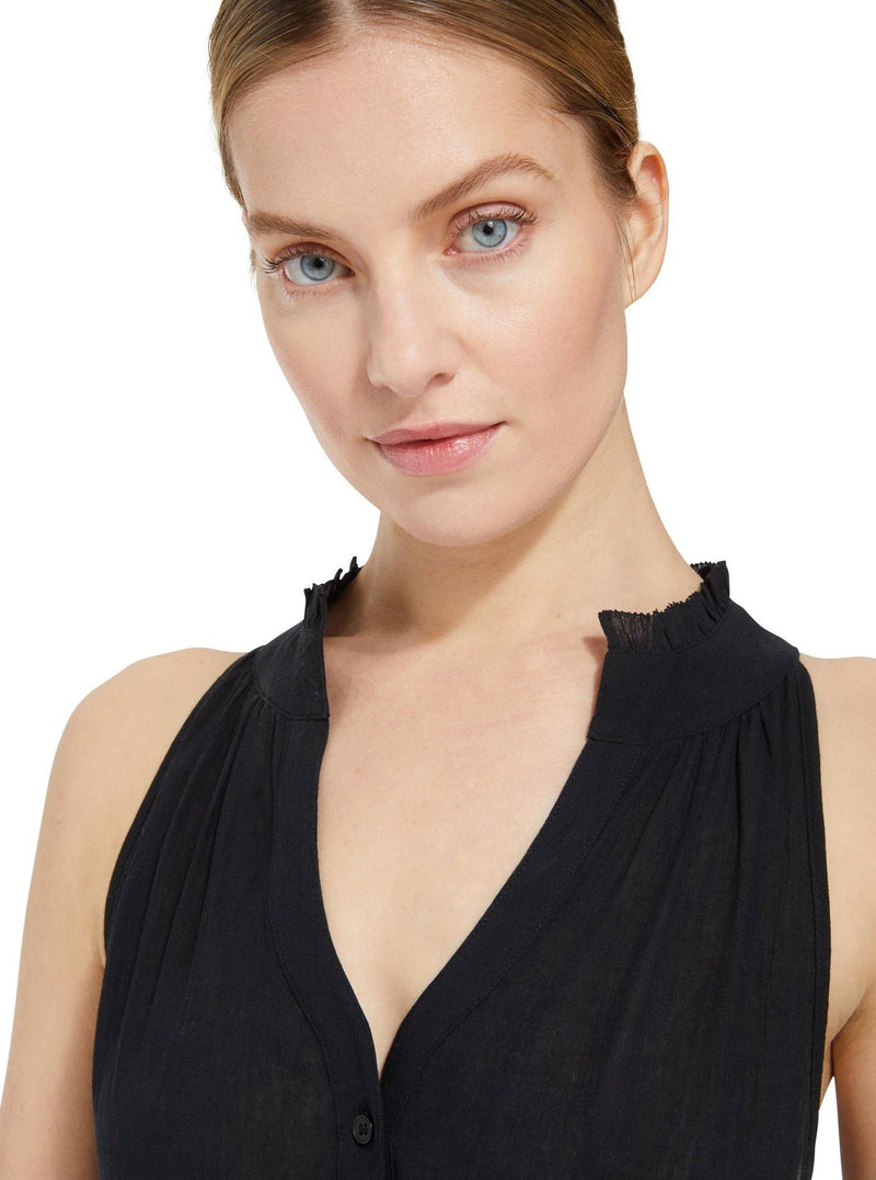 Close up and detailed shot of model wearing a black colored sleeveless, high neck with ruffle detail, buttoned shirt dress.