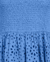 Close-up of a blue dress with textured fabric and eyelet details.