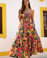 Woman wearing a colorful floral dress standing in front of a white wall with yellow trim.