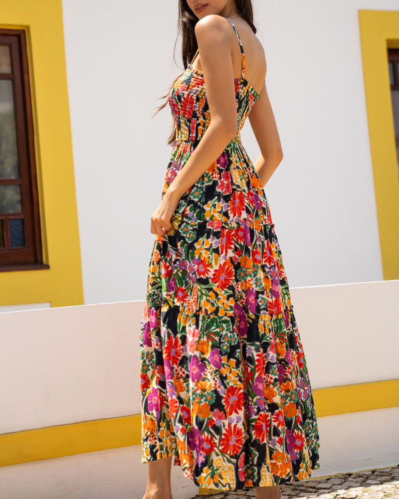 Woman wearing a colorful floral dress standing in front of a white wall with yellow trim.