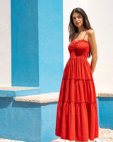 Woman in a red dress standing against a blue and white wall.
