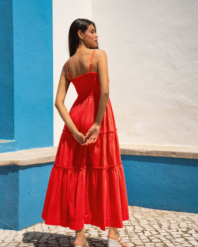 Woman in a red dress standing against a blue and white wall.