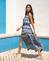 Woman in a blue patterned dress standing against a blue and white wall.