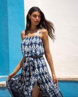 Woman wearing a blue and white patterned dress against a blue and white wall.