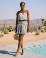 Woman in a floral dress standing by a pool with desert landscape in the background
