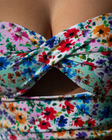 Colorful floral strapless top on a person against a neutral background