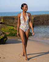 Woman in a colorful swimsuit walking on a beach with ocean in the background